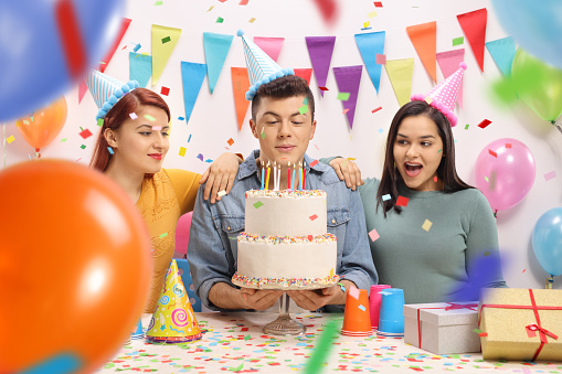 Teenagers with party hats and a cake celebrating a birthday